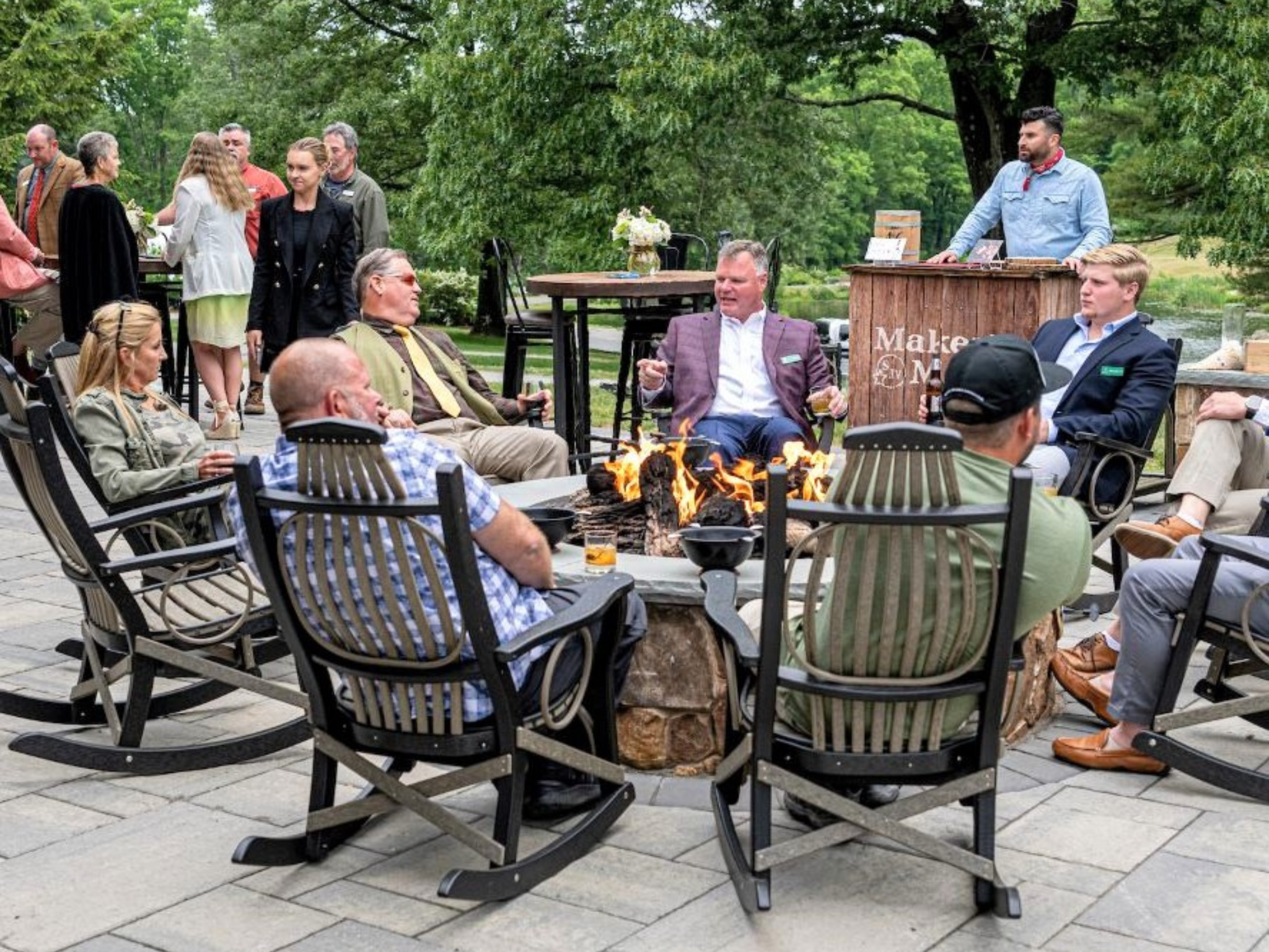 A group of event participants gathered around a fire after the YMCA Sporting Clays event