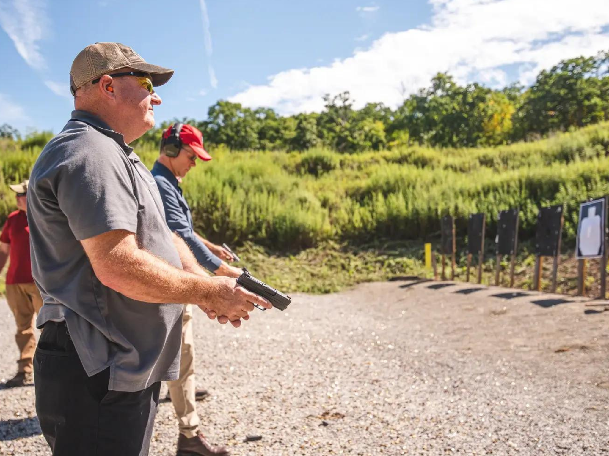 Two men in a row practicing shooting at the YMCA Shooting Clays event