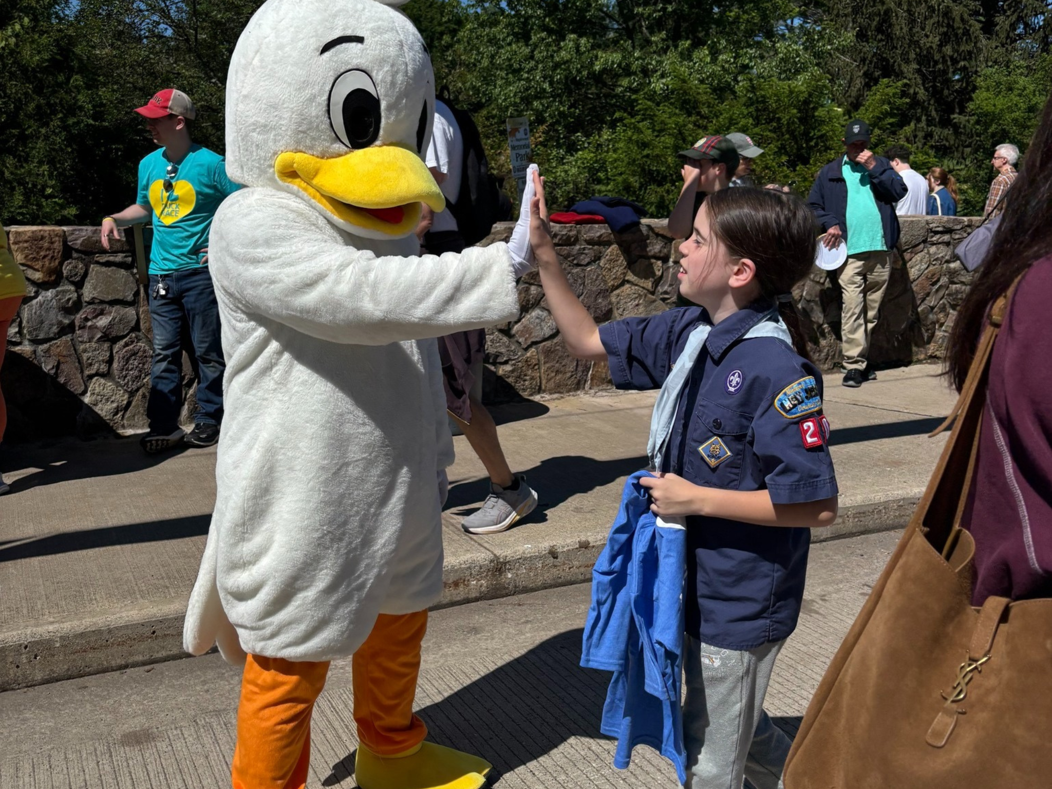 A duck mascot giving a young girl a high five at the South Mountain YMCA Duck Race