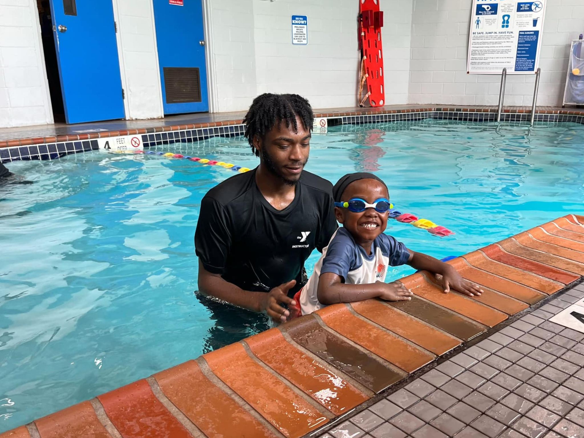 A YMCA instructor helping a small child in the pool at Safety Around Water week