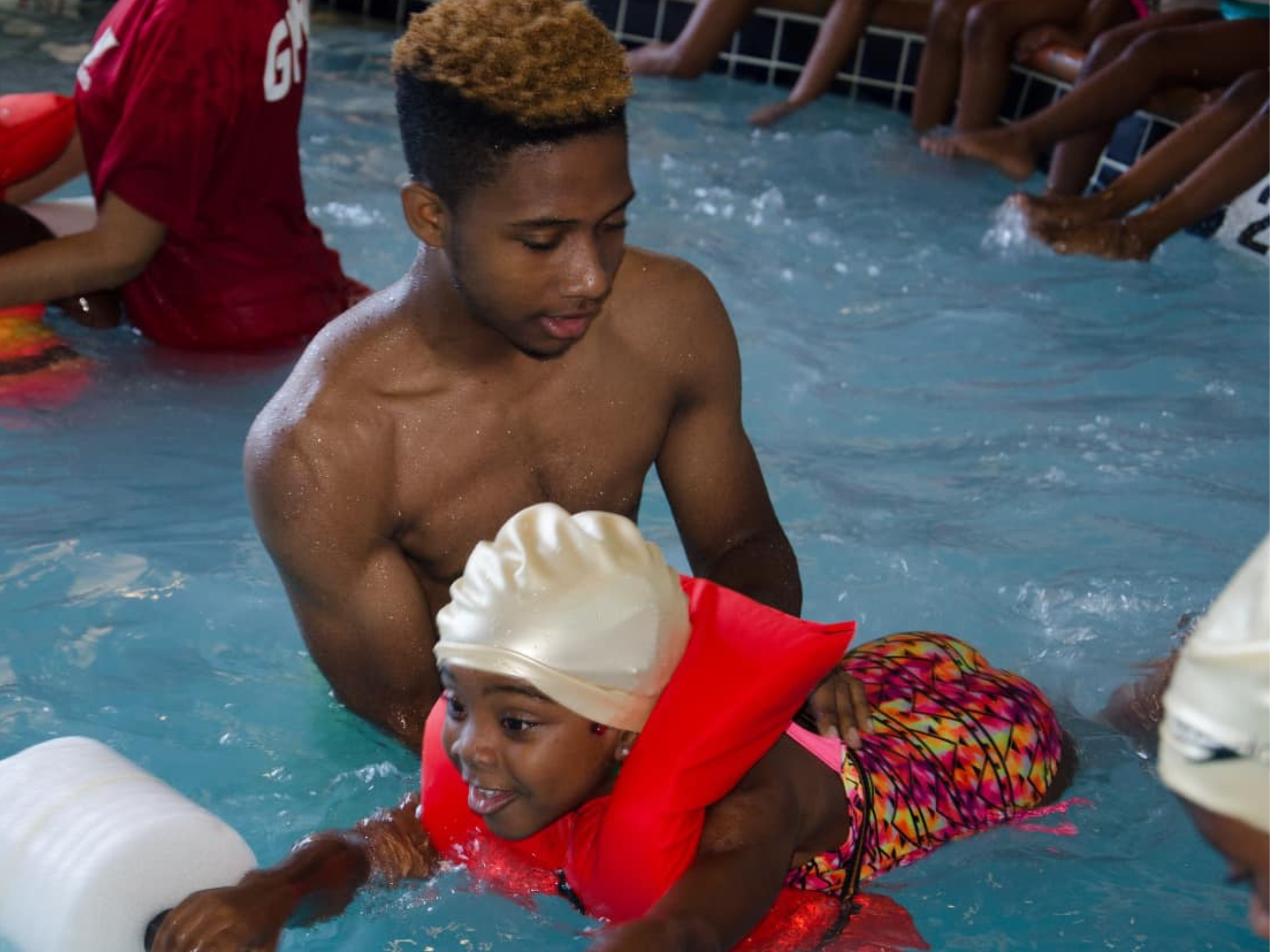 A YMCA instructor helping a young child how to kick her legs at the YMCAs Safety Around Water event